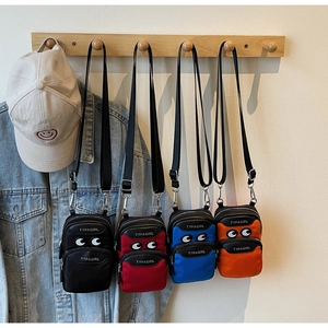 Detail of four colorful nylon crossbody bags with cartoon eyes and adjustable straps