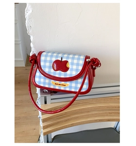 Close-up of plaid wool shoulder bag featuring red apple embroidery and knot strap detail