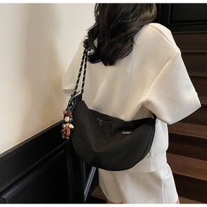 Vista trasera de modelo con bolso de media luna negro con correa estampada y un colgante