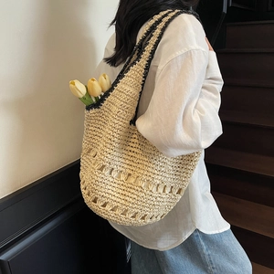 Detail of handwoven straw tote with black contrast shoulder strap and hollow pattern