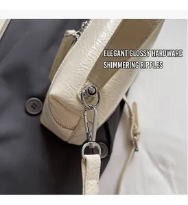 Detailed macro view of cream bucket bag with glossy hardware and wrinkled texture