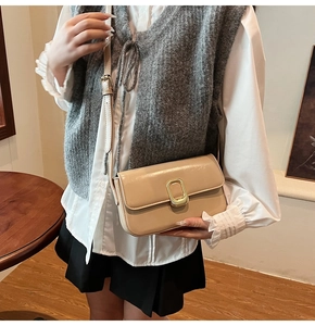 Detalle de bolso de hombro minimalista de cuero beige con hebilla rectangular dorada