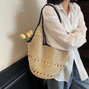 Detailed close-up of straw woven tote bag featuring black trim and intricate hollow pattern