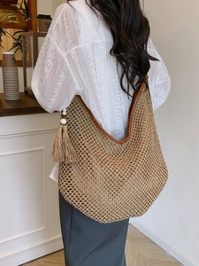 Gewebte Strandtasche mit braunem Lederbesatz und Quastendetail in einem Café-Ambiente