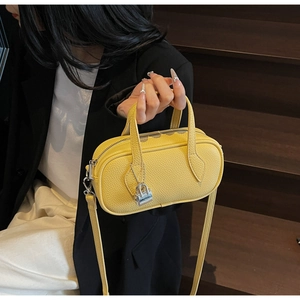 Detailed close-up of yellow lychee-patterned leather texture and silver lock charm
