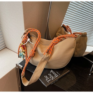 Detalle del bolso hobo con correa de cuerda a rayas y colgante de payaso azul
