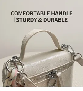 Close-up of cream textured handbag featuring silver zipper and woven rope detail