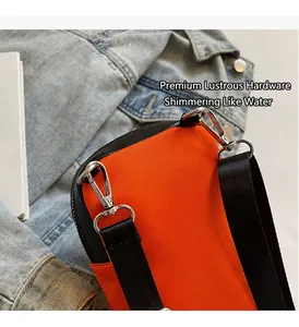Close-up of vibrant orange canvas bag featuring durable silver metal hooks and black strap
