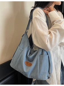 Light blue denim tote bag with brown leather logo patch and large capacity shoulder strap
