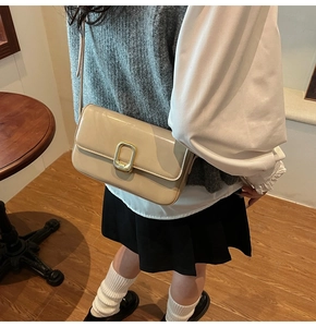 Detalle del elegante bolso bandolera beige con cierre metálico dorado rectangular