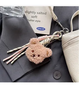 Brown teddy bear plush charm with woven rope detail on white designer handbag