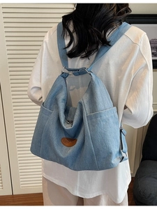 Minimalist light blue denim tote bag with spacious side pockets and leather brand tag