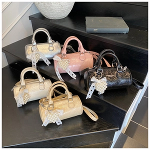 Detail view of mini cylinder handbags in five colors with pearl heart charms and lace
