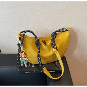 Detalle de bolso medialuna amarillo con correa de cuerda y colgante de muñeca