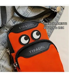 Detail of orange nylon phone bag featuring cartoon eyes and adjustable black strap