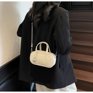 Close-up of cream mini pillow bag featuring lychee texture and metallic lock detail