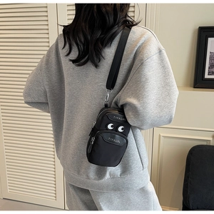 Detail of a black nylon crossbody phone bag with eye patches and adjustable strap