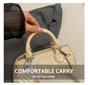 Close-up of cream barrel bag with textured faux leather and elegant pearl charm detail