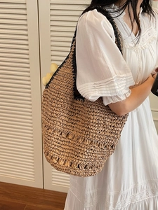 Large woven straw shoulder bag for women featuring intricate patterns and black handles