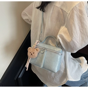 Crossbody light blue bucket bag with pleated texture and brown plush bear charm
