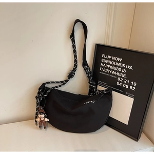 Detalle del bolso bandolera negro de media luna con correa de cuerda y adorno