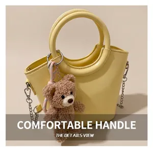 Dettaglio della borsa a secchiello crema in pelle liscia con charm a forma di orso