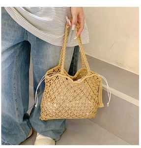 Detail of straw tote bag featuring drawstring closure and stylish side fringe tassels