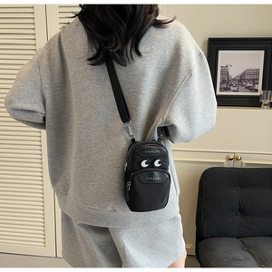 Detail of black crossbody phone bag with signature eye pattern and double zipper design