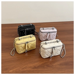 Detailed view of four mini vanity bags in black, pink, yellow, and white quilted leather
