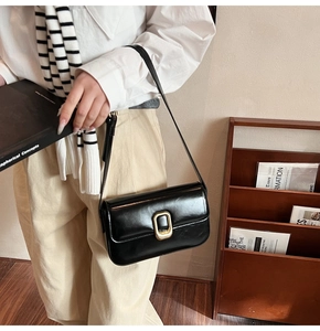 Bolso de hombro negro con hebilla dorada en una escena de moda francesa minimalista