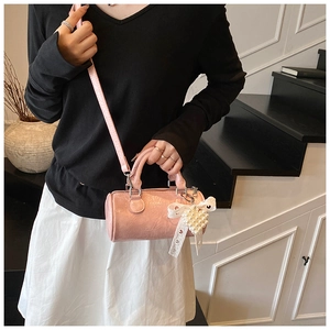 Detailed macro view of pink cylinder crossbody bag with lace bow and pearl heart charm