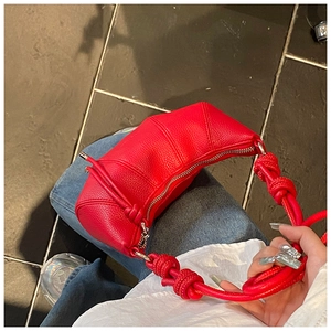 Detail der roten Croissant-Tasche mit Litschimuster, Knotengriff und Silber-Reißverschluss
