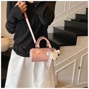 Pink mini cylinder bag featuring shiny pleated texture and a white lace bow detail