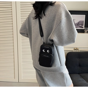 Detail of black mini nylon crossbody bag with dual zipper layers and TYPAGIRL logo