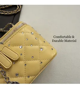 Detail of yellow quilted leather box bag with rhinestone embellishment and chain strap