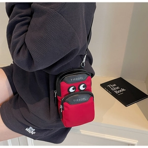 Detail of red and black crossbody phone bag with double zippers and eye motif