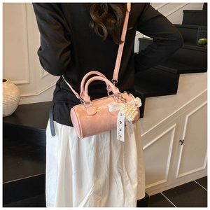 Pink cylinder bag featuring shiny pleated texture and pearl heart charm detail