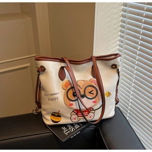 Close-up of white lychee leather tote bag with cartoon bear print and brown handle straps