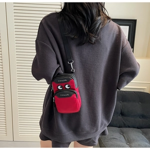Detail of red canvas phone bag with cartoon eye design and adjustable black shoulder strap