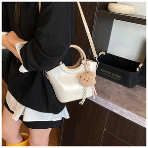 Detail of cream white bucket bag with 'FASHION & YM' text and a cute brown bear charm