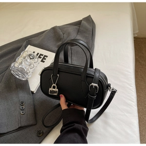 Detail shot of black lychee grain leather mini bag with silver charm and slim strap