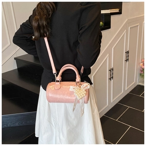 Detail of pink cylindrical handbag with pearl heart charm and lace bow decoration