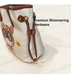 Detail of white lychee leather tote bag with bear print and gold hardware buckle