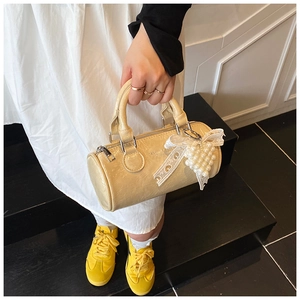 Detail of cream cylinder handbag with glossy oil wax leather and pearl lace charm