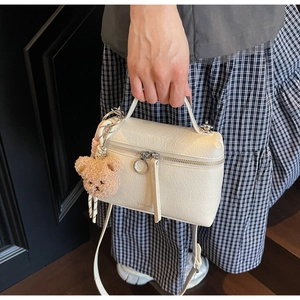 Detail of cream white textured crossbody bucket bag with cute brown bear charm