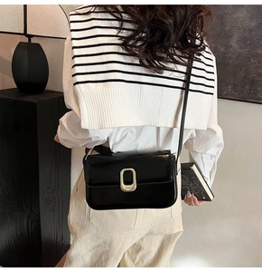 Detalle de bolso de hombro negro charol con hebilla dorada vintage llevado por una modelo