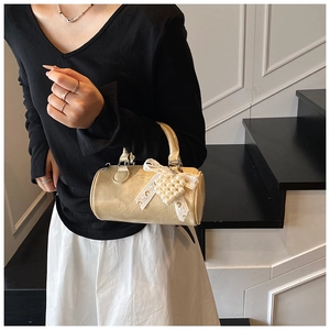 Detail of vintage beige pleated cylindrical bag with lace bow and heart pearl charm