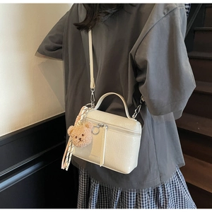 Detail of cream crossbody bucket bag with crinkled leather and brown plush bear charm