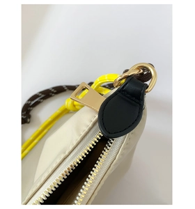 Detail of cream nylon bag featuring golden zipper and colorful woven rope handle