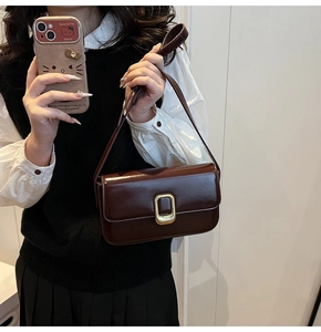 Detalle del bolso de hombro en cuero brillante marrón oscuro con hebilla dorada